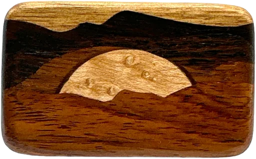 A rounded rectangular buckle inlaid in colored woods, showing a desert butte against a striped sky.
