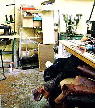 The back workshop: the old sewing machine, the press, and hides stacked against the bench.