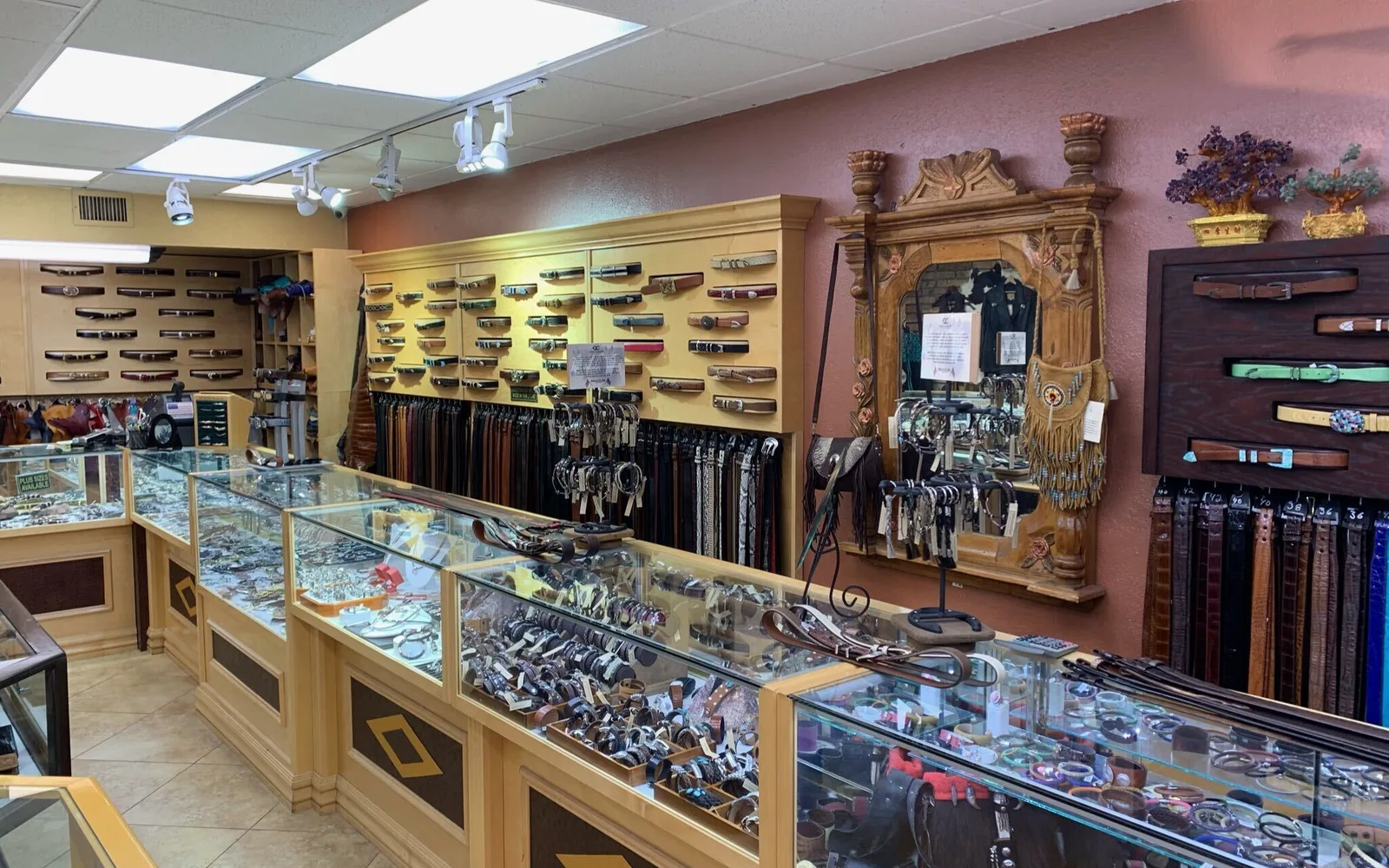 Inside the shop: the buckle wall, racks of finished belts and the glass cases.